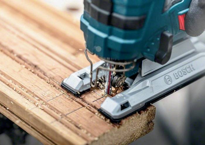 Eine Stichsäge, die durch ein Holzstück schneidet und präzises Handwerk sowie Konzentration auf Holzbearbeitungsfähigkeiten demonstriert.