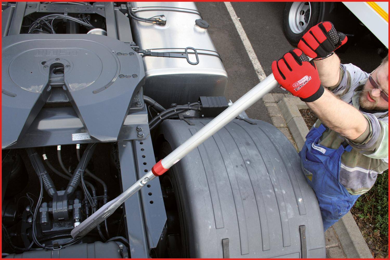 Eine Person, die einen Drehmomentschlüssel verwendet, um einen Bolzen am Fahrgestell eines Lastkraftwagens zu überprüfen oder einzustellen, wobei Wartungs- oder Mechanikarbeiten hervorgehoben werden.