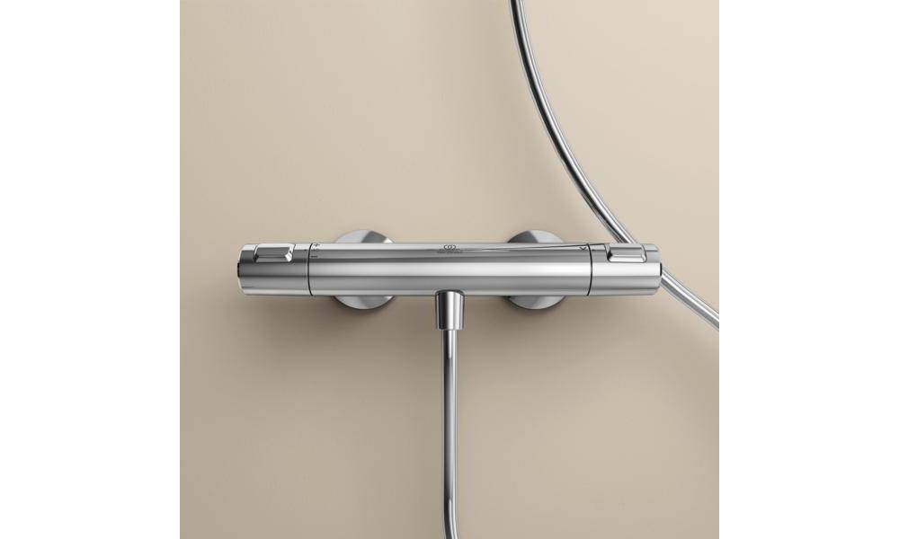 Chrom-Thermostat-Duscharmatur mit zwei runden Wandhalterungen und angeschlossenen Schläuchen an einer beigefarbenen Wand.