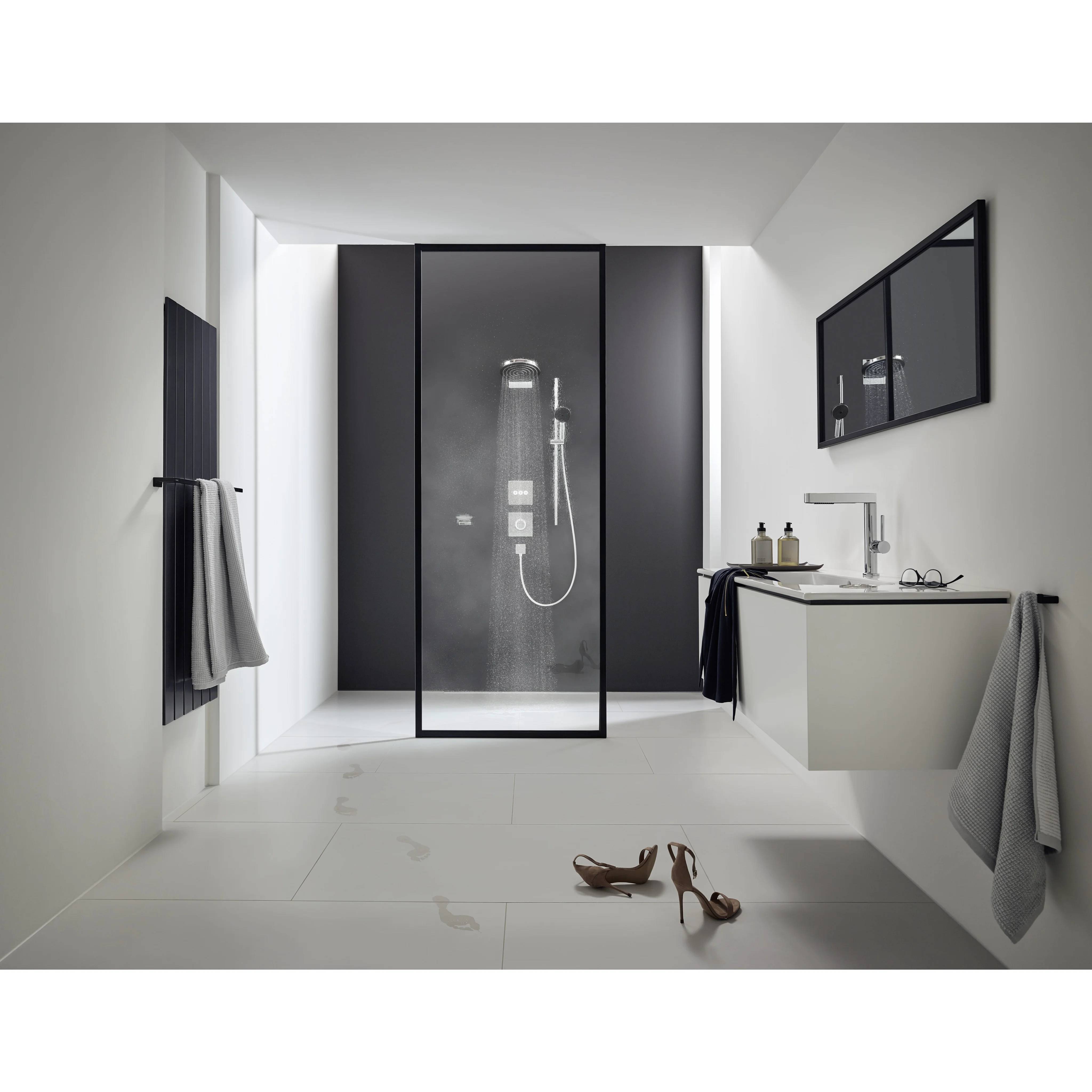 Modernes minimalistisches Badezimmer mit einer Glastdusche, schwebender Waschtisch, Wandspiegel, Handtüchern und Schuhen auf dem Boden.