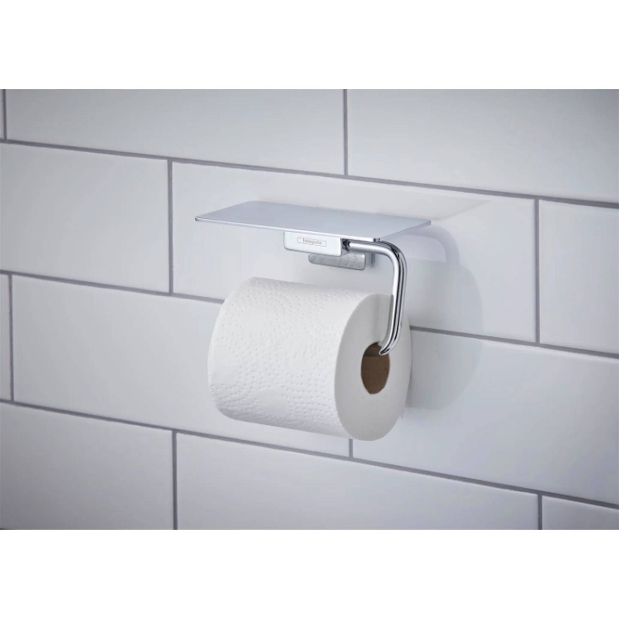 Wandmontierter Toilettenpapierhalter mit einer Rolle weißem Toilettenpapier vor einer hellgrauen gefliesten Wand.