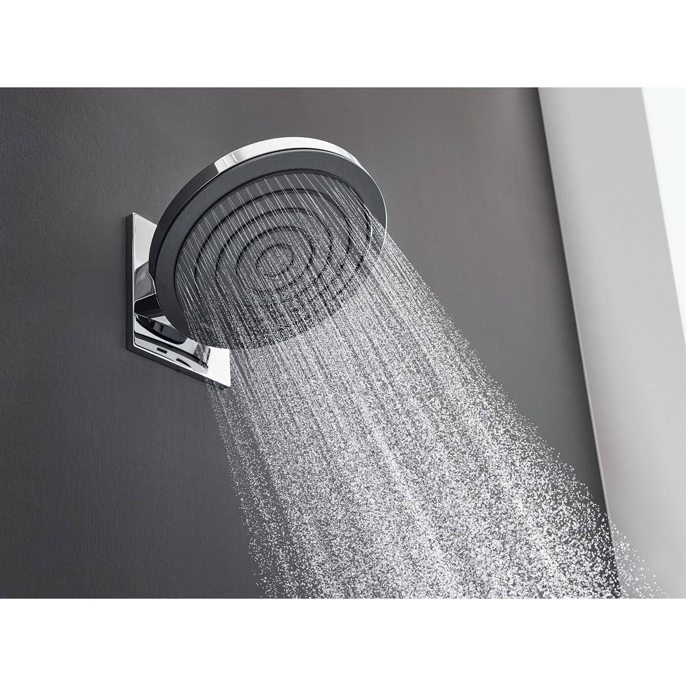 Verchromter an der Wand montierter Duschkopf, der Wasser in einem modernen Badezimmer sprüht, mit großem rundem Gesicht und quadratischer Basis an einer grauen Wand.
