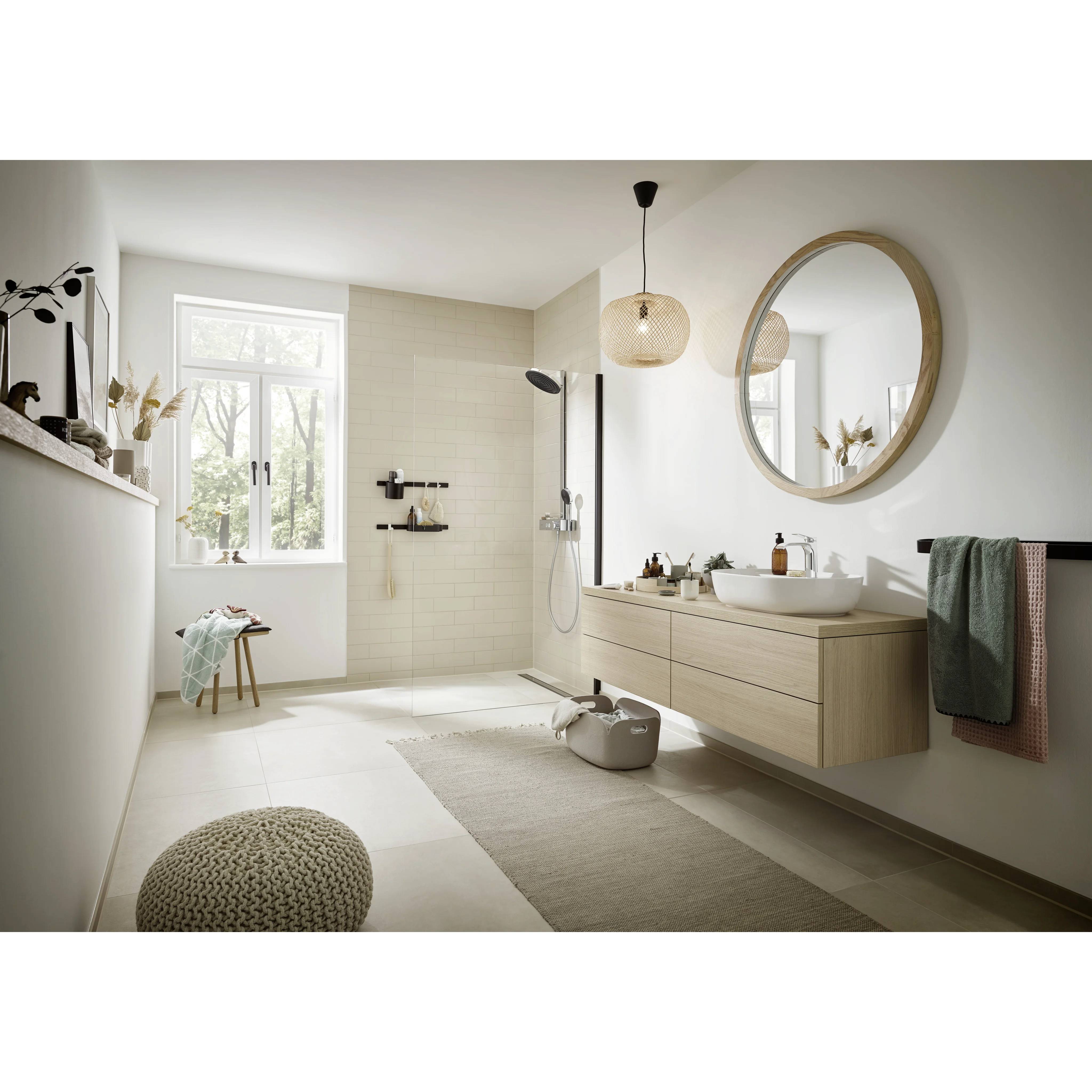 Helles modernes Badezimmer mit begehbarer Dusche, schwebendem Waschtisch, rundem Spiegel und natürlichen Holzakzenten in einem minimalistischen Beige- und Weiß-Interieur.
