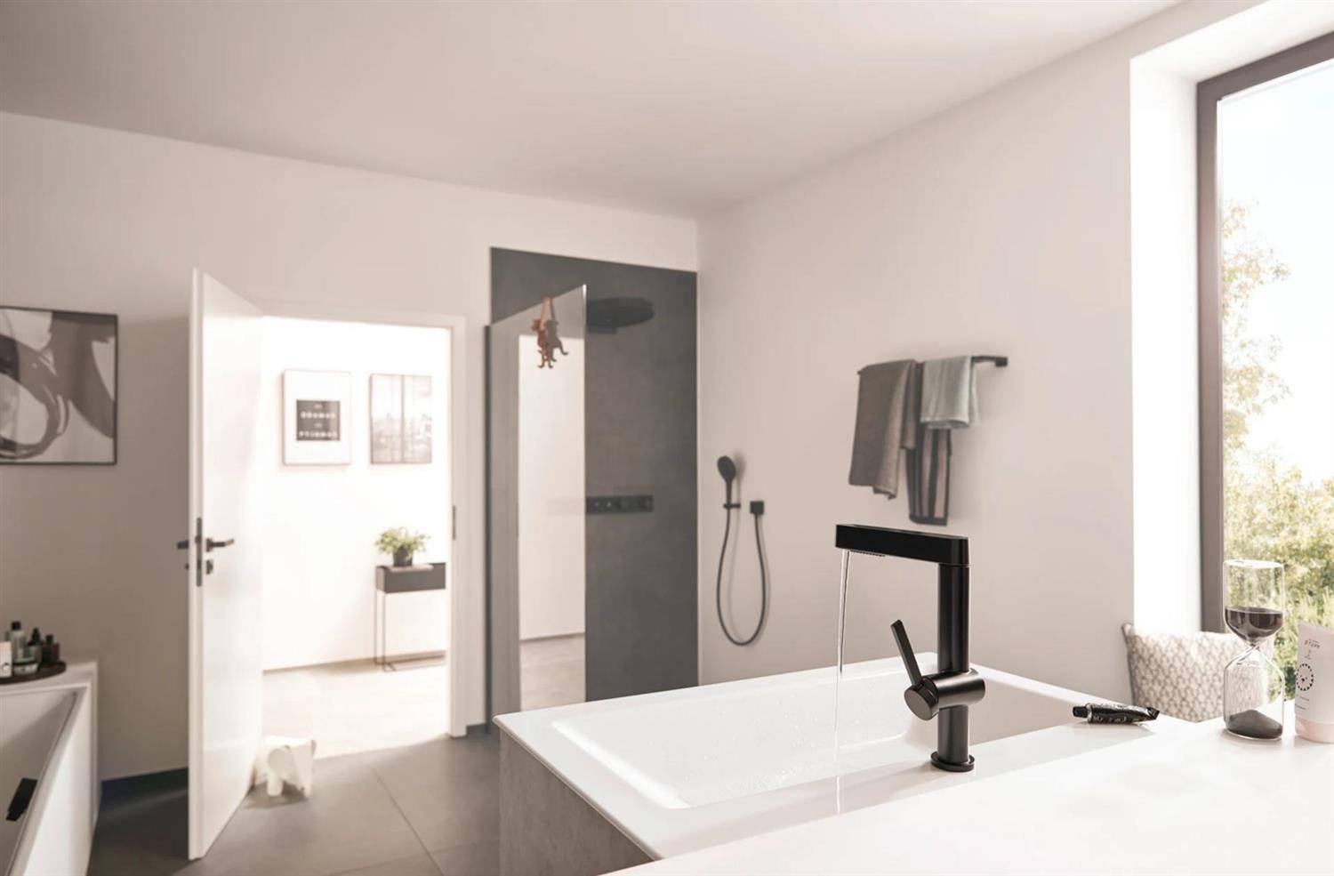 Modernes Badezimmer mit einer freistehenden Badewanne und schwarzem Wasserhahn, begehbare Dusche, offene Türöffnung zu einem hellen angrenzenden Raum und ein Fenster mit einem Weinglas auf der Fensterbank.