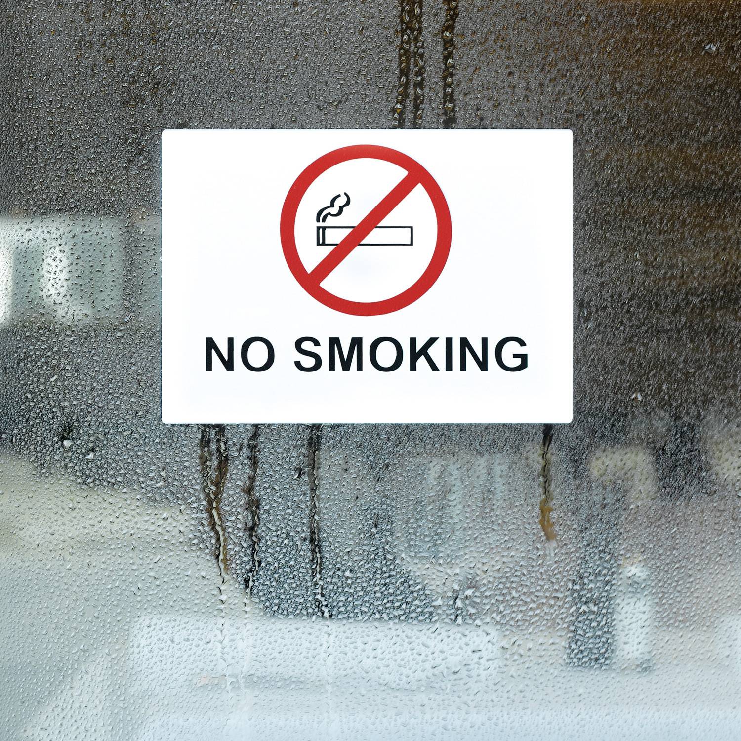 Nichtraucher-Schild auf einer nebligen Glastür, mit einem durchgestrichenen Zigarettensymbol und dem Text „RAUCHEN VERBOTEN".