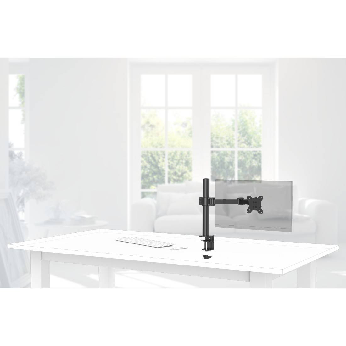 Ein an einem weißen Tisch montierter Monitorarm auf dem Schreibtisch in einem hell erleuchtetem Wohnzimmer, der einen Flachbildschirm neben einem Sofa und Fenstern hält.