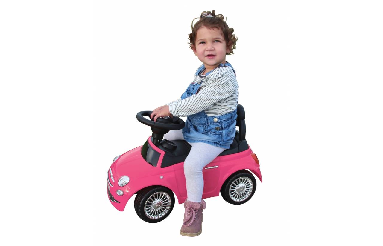 Junges Kind sitzt auf einem rosa Rutschauto gegen einen weißen Hintergrund.