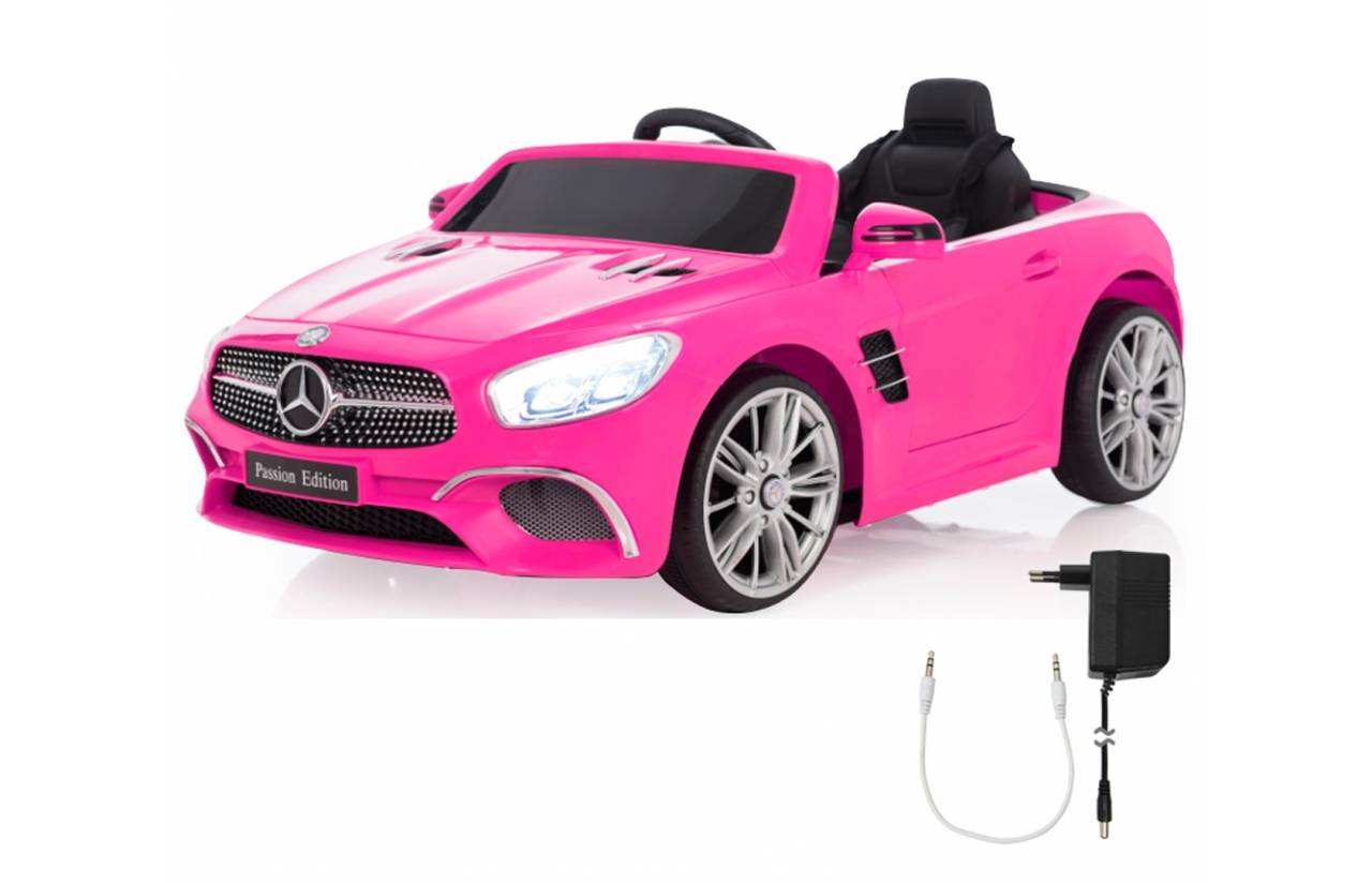 Rosa Mercedes-ähnliches Kinderfahrzeug mit Verdeck und Ladegerät daneben auf weißem Hintergrund gezeigt.