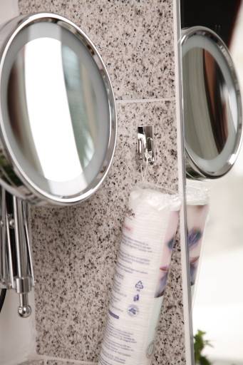 Zwei an der Wand montierte runde Spiegel reflektieren eine Badezimmerablage mit einer in Kunststoff eingewickelten Toilettenpapierrolle und einem Teil eines Waschbeckens.