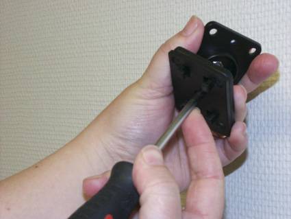 Eine Person verwendet einen Schraubendreher, um eine schwarze Metallmontageklammer an einer anderen Klammer oder einem Paneel zu befestigen.