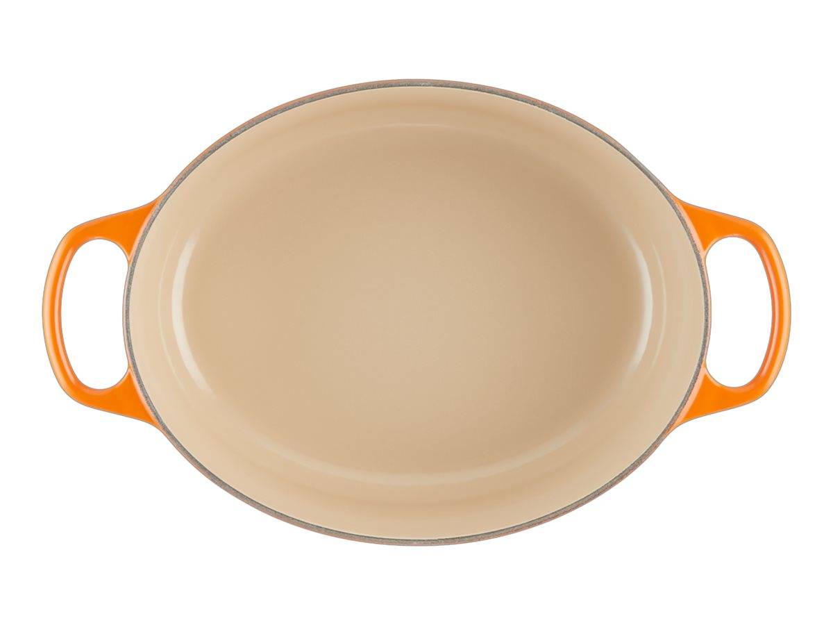 Ovale beige Auflaufform mit orangefarbenen Griffen auf weißem Hintergrund.