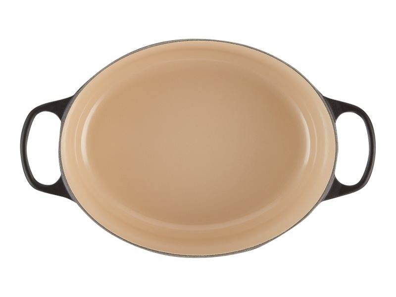 Ovale beige Auflaufform mit zwei schwarzen Seitengriffen auf weißem Hintergrund.