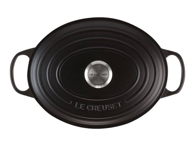 Ovale schwarze Le Creuset Gusseisen-Kasserolle mit zwei seitlichen Griffen und einem silbernen Knauf in der Mitte.