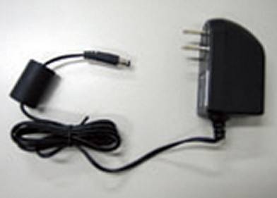 Schwarzer Wechselstromadapter mit angebrachtem Kabel und Stecker auf hellem Hintergrund.
