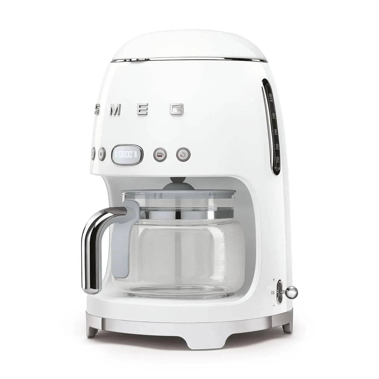 Weißer SMEG Tropfkaffeemaschine mit Glaskanne und Chromgriff auf neutralem Hintergrund.