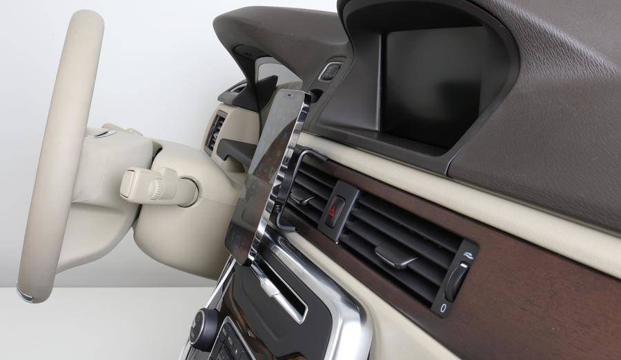 Eine Nahaufnahme eines Armaturenbretts eines Autos mit einem ausgelösten Lenkrad-Airbag auf der linken Seite und dem Mittekonsolen-Bildschirm sowie den Lüftungsschlitzen auf der rechten Seite.