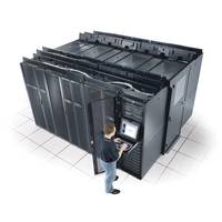Person, die einen Computer-Terminal vor einem großen Server-Datencenter-Rack-Gehäuse bedient.