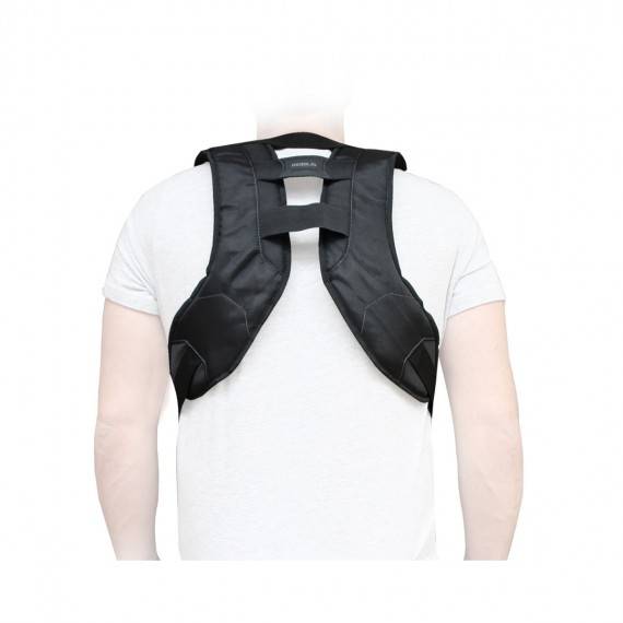 Schwarzer Schulterhaltungskorrektor, über einem weißen T-Shirt auf dem Rücken einer Person getragen, mit gepolsterten Riemen, die sich über den oberen Rücken kreuzen.