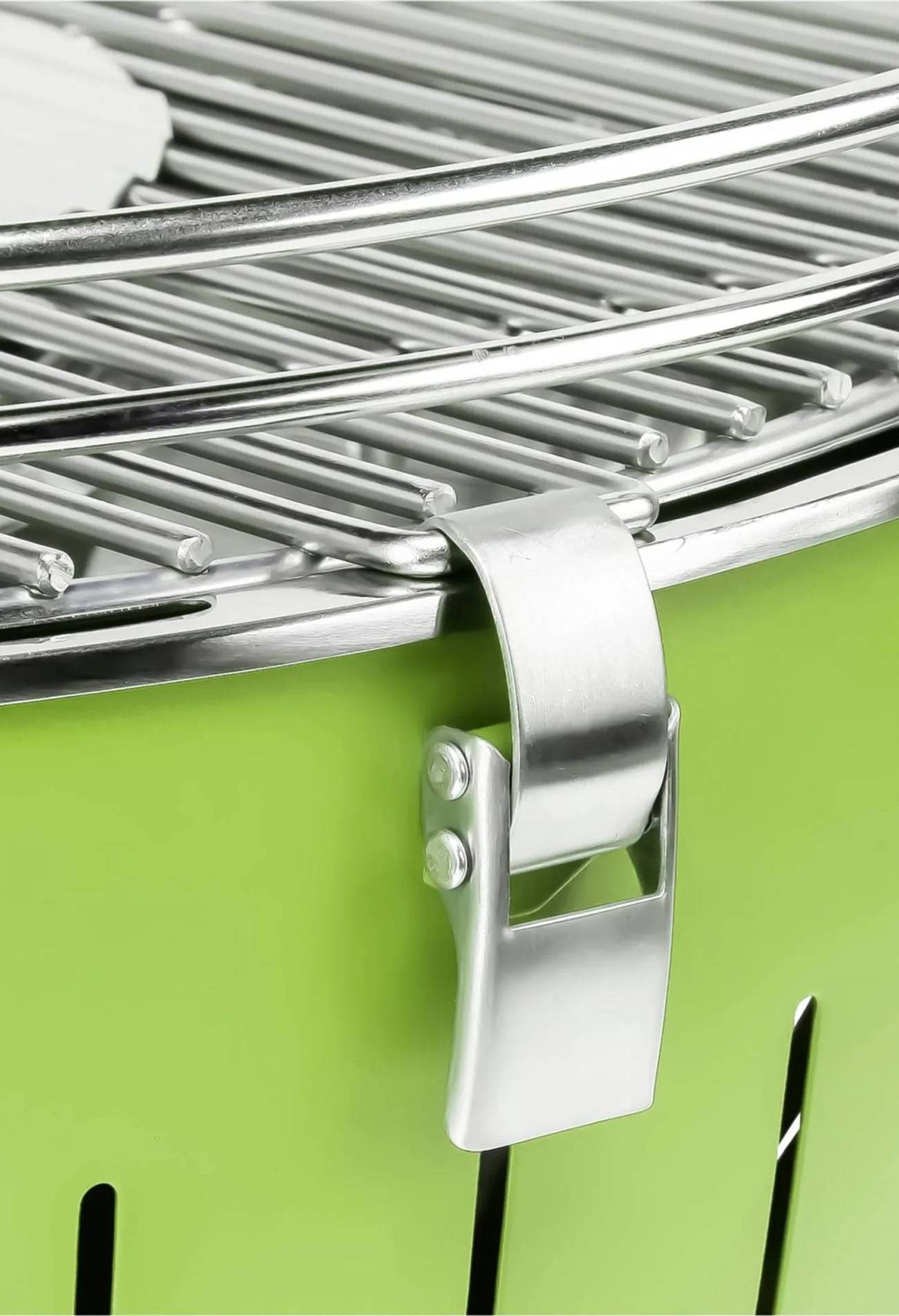 Nahaufnahme eines grünen Kugelgrills mit einem verchromten Grillrost und einer Metallverriegelung an der Vorderseite.