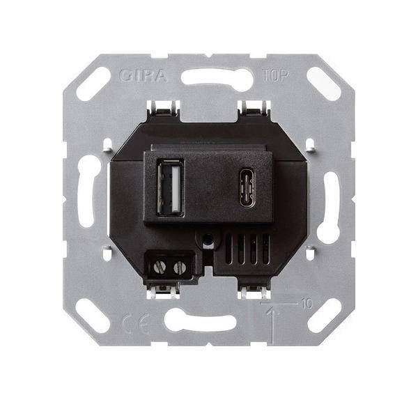 Eine Dual-USB-Wandsteckdose mit einem Standard-USB-Anschluss und einem USB-C-Anschluss, eingebaut in einen quadratischen Metallrahmen, der für die Wandmontage konzipiert ist.