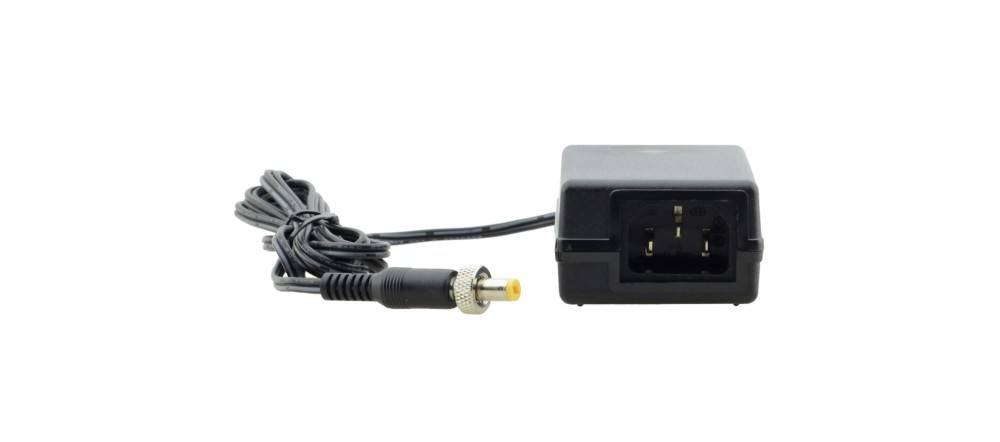 Ein schwarzes Netzteil mit angeschlossenem Kabel und Stecker mit gelber Spitze, das für elektronische Geräte verwendet wird, vor einem weißen Hintergrund.