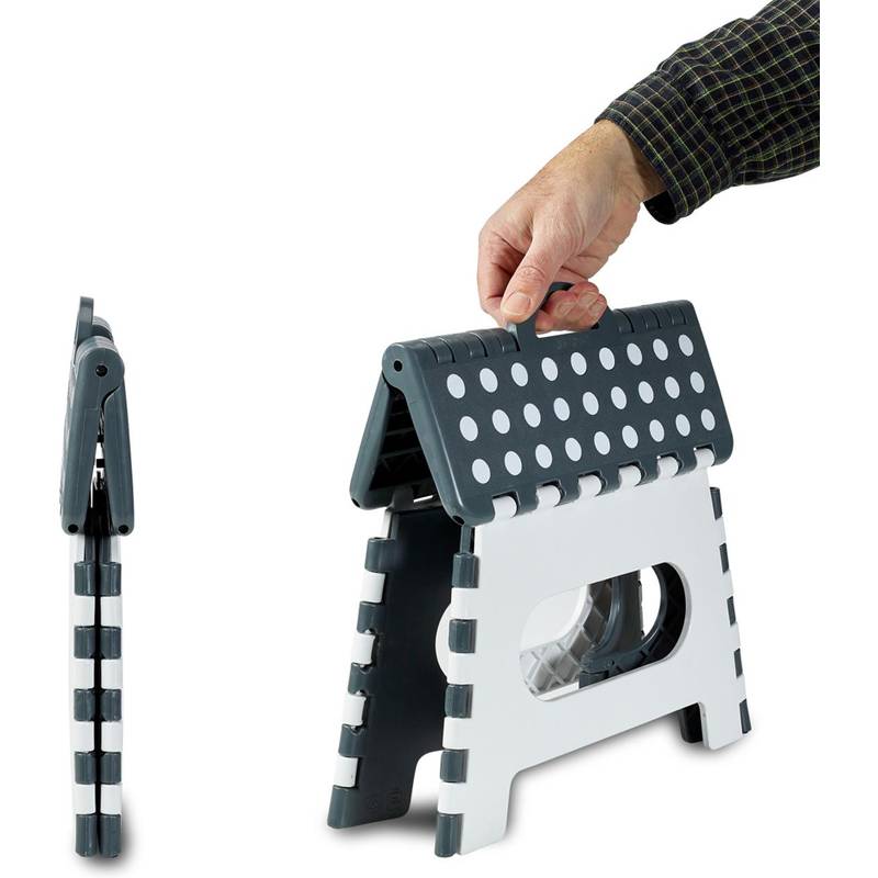 Eine Hand, die einen schwarzen und weißen Hocker mit Punktmuster zusammenklappt und dabei sein kompaktes und tragbares Design präsentiert.