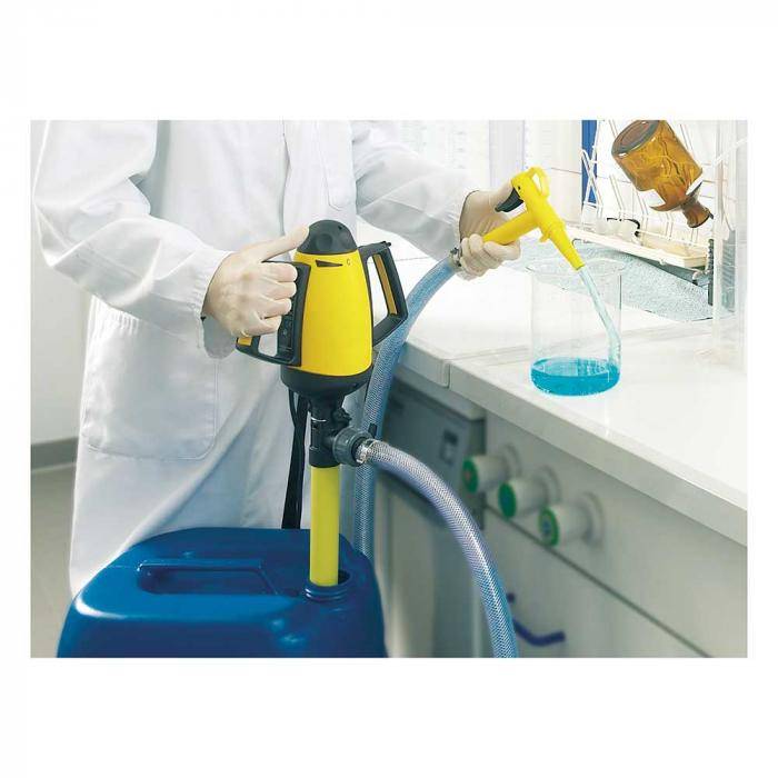 Wissenschaftler in einem Labor gießt blaue Flüssigkeit aus einem gelben Spender in ein Becherglas neben einem Waschbecken, mit einem blauen Behälter und Schläuchen im Vordergrund.