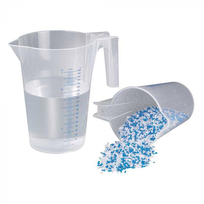 Zwei Kunststoff-Messbehälter, einer aufrecht mit Wasser und einer umgestürzt, aus dem blau-weiße Pellets verschüttet werden.