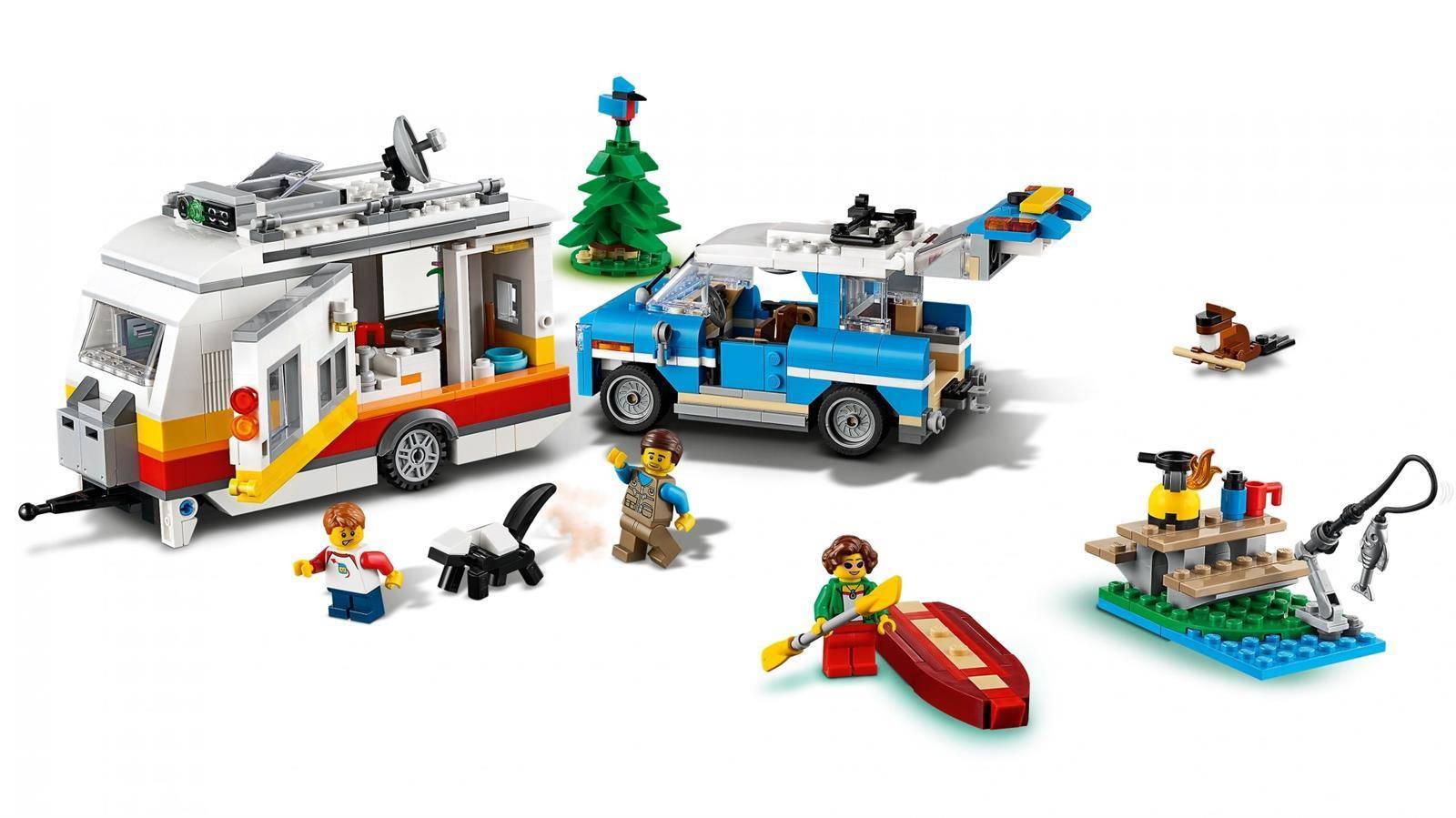 LEGO-Campingszene mit einem Wohnmobil, blauem Auto, Baum, Kanu, Picknick-Floss und Minifiguren auf weißem Hintergrund.
