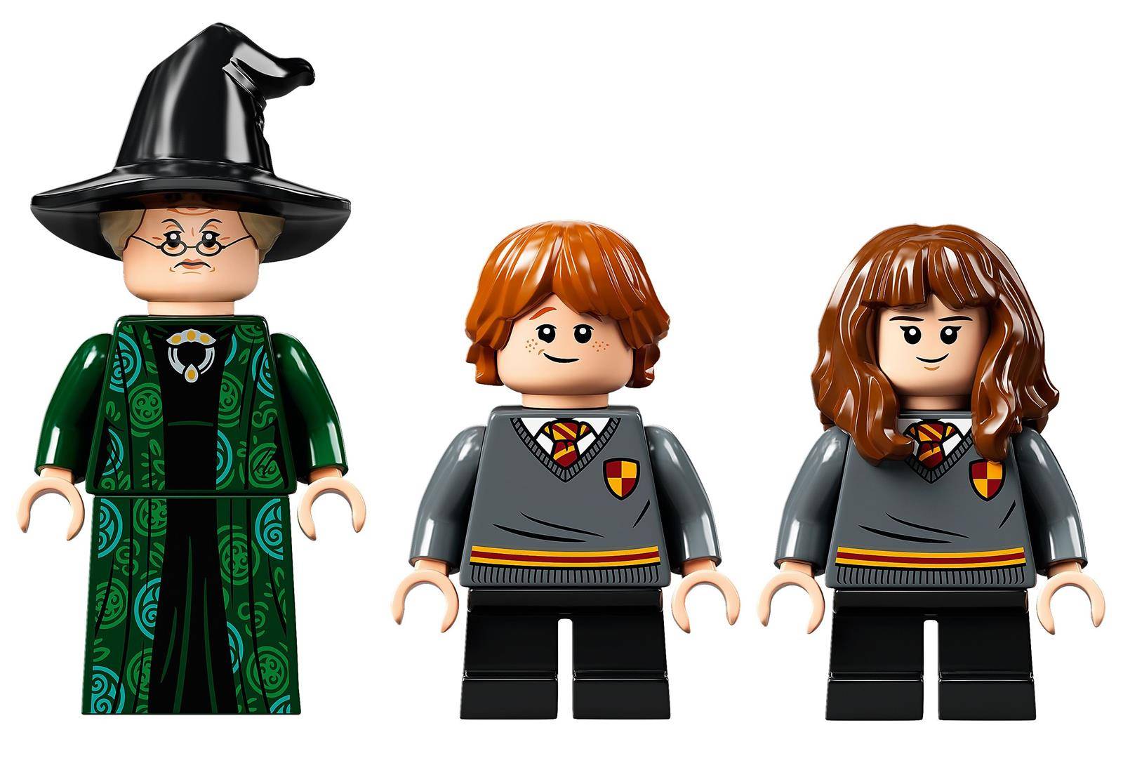 Drei Lego-Figuren: eine Person in einem grünen Gewand und spitzem Hut sowie zwei Kinder in Schuluniformen. Alle haben neutrale Gesichtsausdrücke.