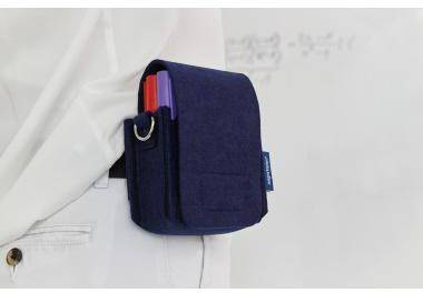 Dunkelblauer Beutel, der an einer weißen Hemdtasche befestigt ist und einen rot und violett gefärbten Stift enthält.