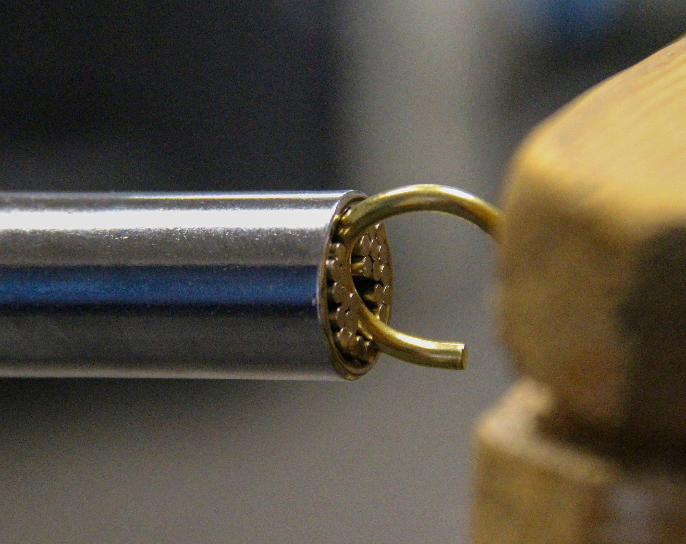 Eine Nahaufnahme eines Kugellagers, das mit einer metallischen Stange verbunden ist und die komplizierten Mechanismen und Teile im Detail zeigt.