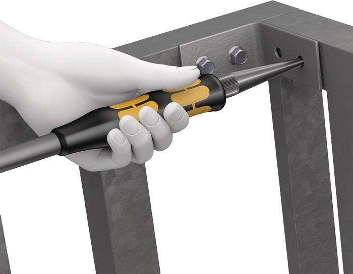 Eine Hand, die einen Schraubendreher hält und eine Schraube in einen Metallrahmen dreht, veranschaulicht die Montage oder Reparatur von industrieller Ausrüstung.