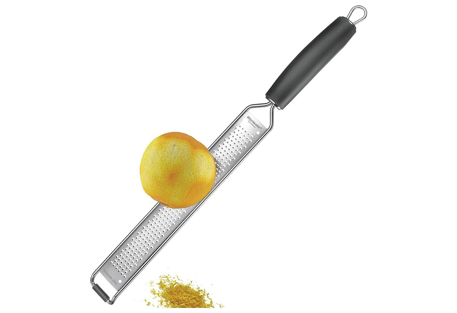 Ein Metall-Reibe mit schwarzem Griff, der eine Zitrone hält. Zitronenzest ist daneben abgebildet. Ideal zum Abreiben von Zitrusfrüchten.