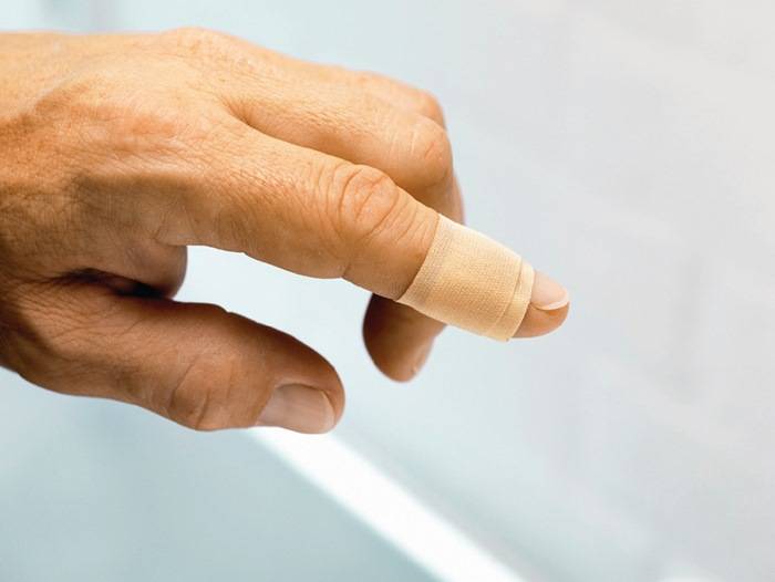 Ein Nahaufnahmefoto einer Hand mit einem Verband, der um den Zeigefinger gewickelt ist, was auf eine Verletzung oder Schutzmaßnahme hindeutet.