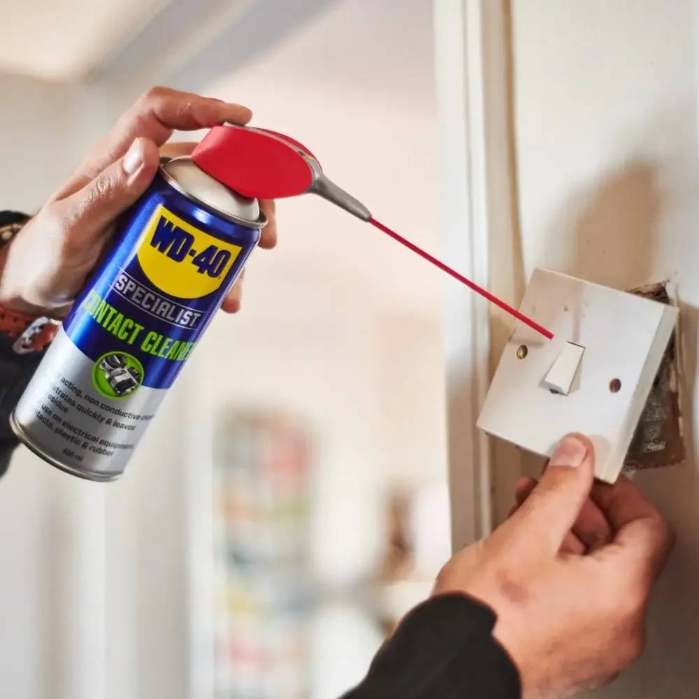 Mit der Hand WD-40 Specialist Kontaktreiniger in einen Wandlichtschalter sprühen, um elektrische Kontakte zu reinigen.