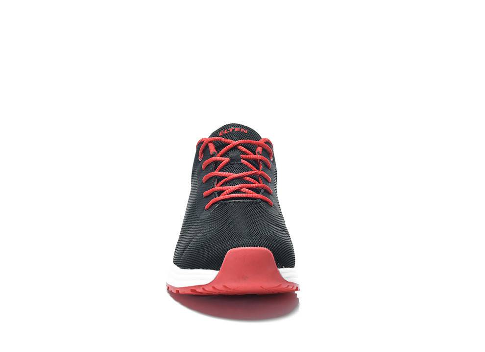 Ein schwarzer Sneaker mit roten Schnürsenkeln und einer weißen Sohle wird von vorne vor einem einfarbigen Hintergrund gezeigt.