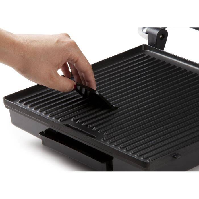 Hand, die den Griff eines schwarzen elektrischen Grills oder Sandwichmakers auf weißem Hintergrund hebt.