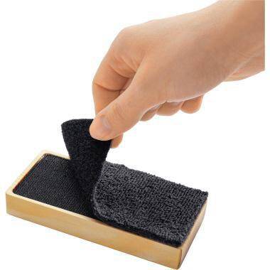 Hand peelt einen schwarzen Klettverschlussstreifen von einem kleinen rechteckigen Block ab.