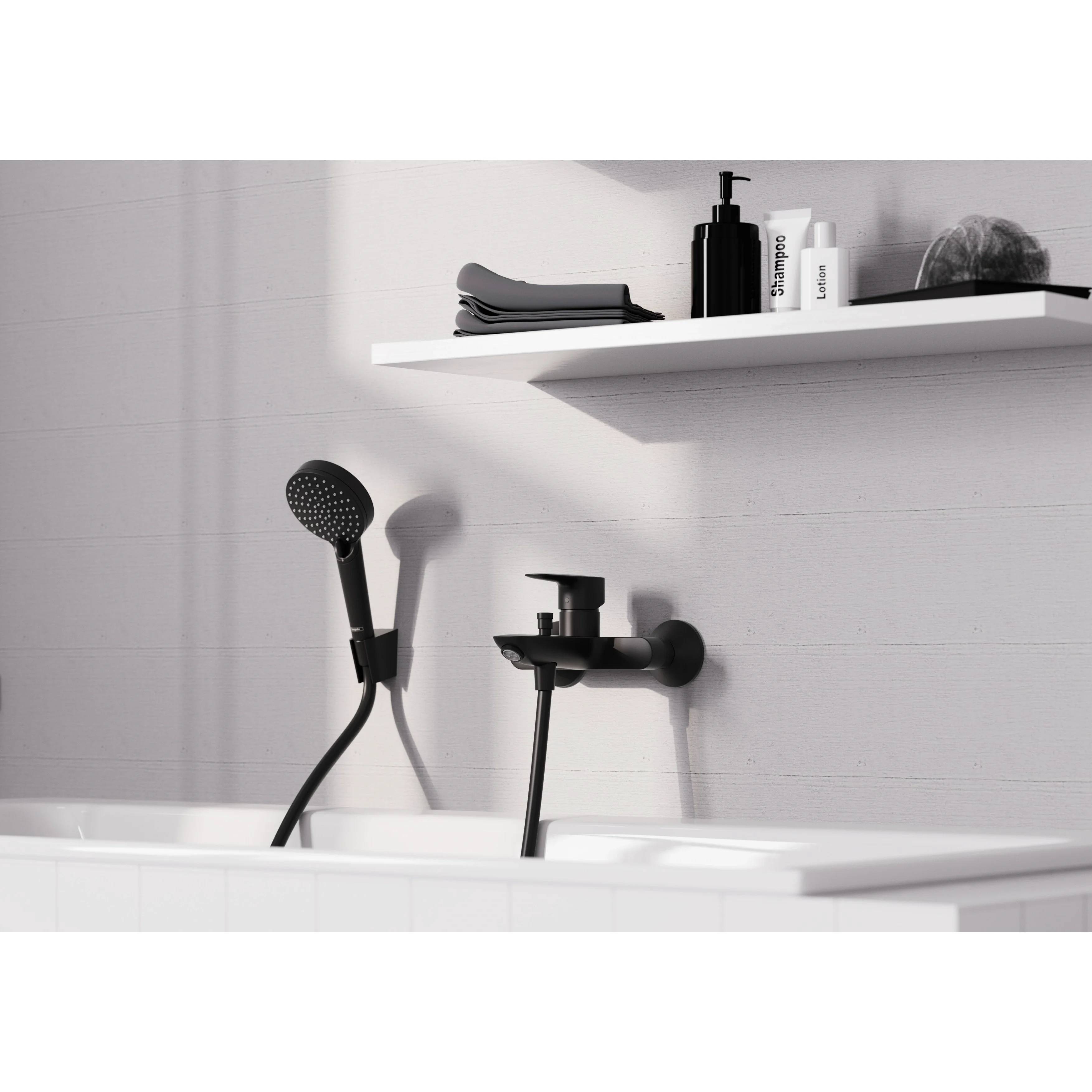 Modernes Badezimmer mit an der Wand montierten schwarzen Duscharmturen, einer weißen Badewannenkante und einem Regal mit Toilettenartikeln und Handtüchern.