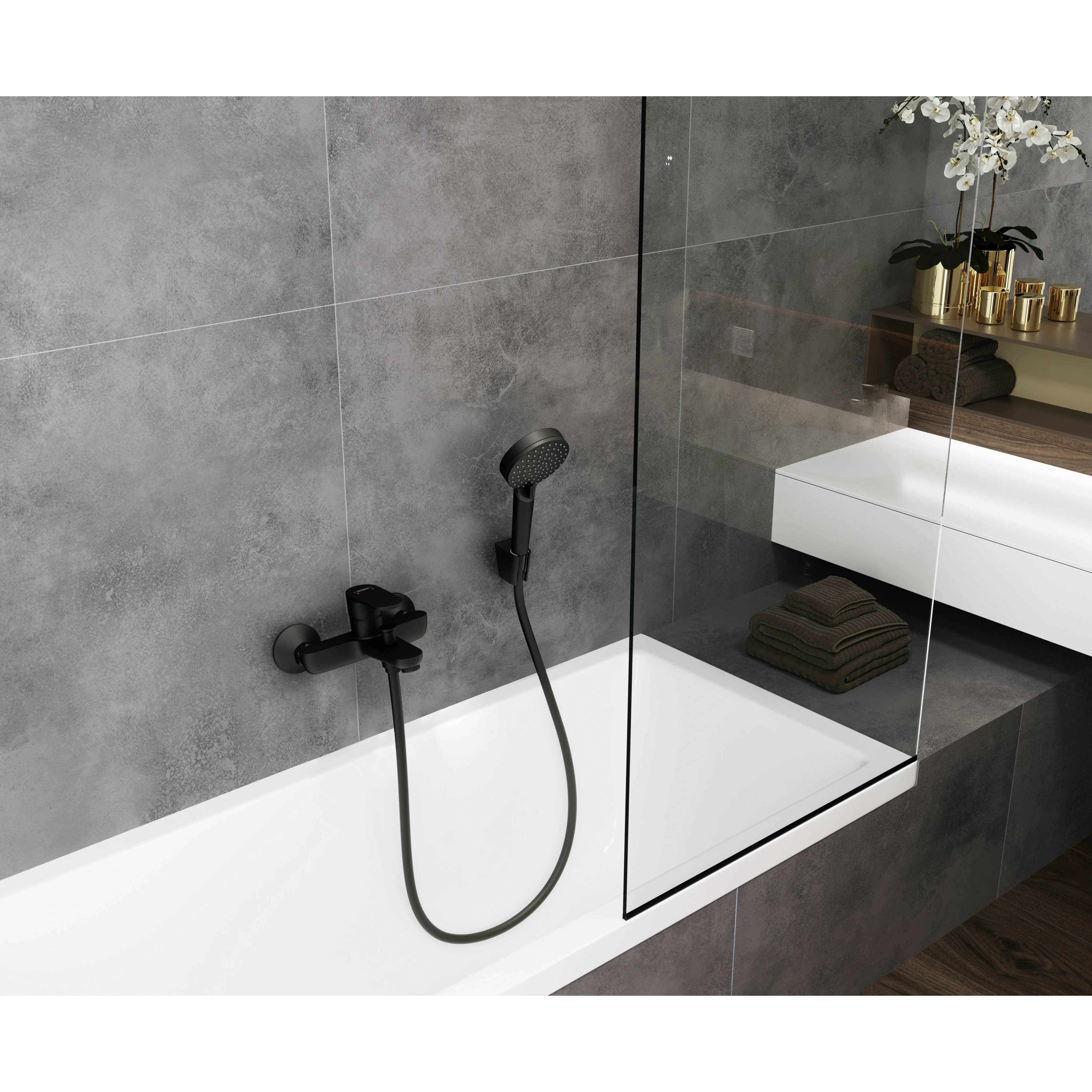 Modernes Badezimmer mit freistehender Badewanne, schwarzer wandmontierter Dusche, Glastrennwand, grauen Fliesenwänden und weißem Waschtisch mit Dekoration
