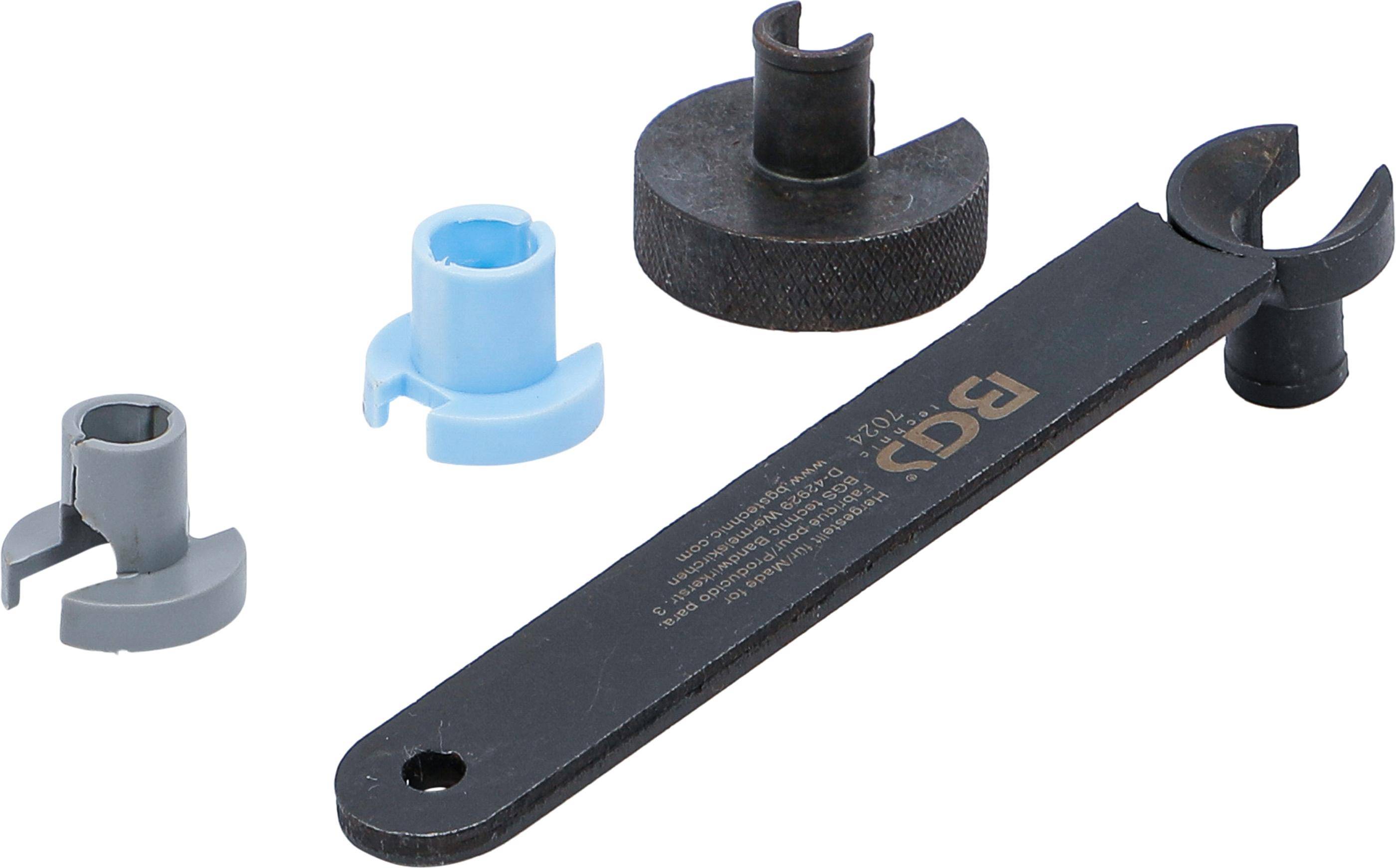 Ein schwarzer Metallschlüssel mit der Aufschrift 'BGS' neben einem schwarzen Rundgewicht und einem hellblauen Abstandshalter, der zum Festziehen oder Justieren von Komponenten verwendet wird.