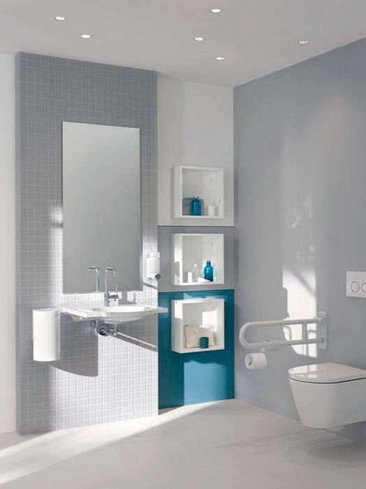 Modernes Badezimmer mit Waschbecken, großem Spiegel und Wandaufbewahrung. Weiß und Petrol-Design mit Haltegriff in der Nähe der Toilette, in natürlichem Licht getaucht.