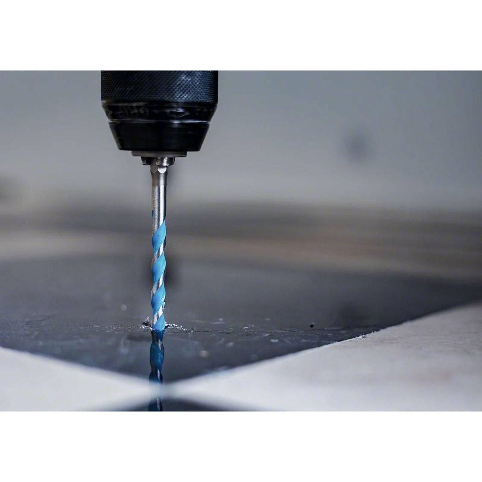 Ein Nahaufnahmefoto eines blauen Bohrers, der in eine glänzende Metalloberfläche schneidet und Reflexionen erzeugt. Der Hintergrund ist unscharf, wodurch der Fokus betont wird.