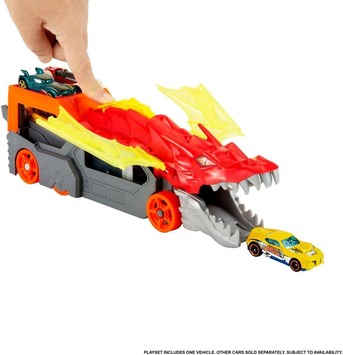 Kind schiebt Spielzeug-Drachenanhänger mit offenen Kiefern und setzt ein gelbes Spielzeugauto frei; zwei weitere Autos fahren oben auf.