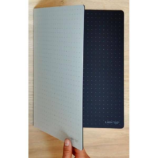 Zwei gepunktete Notizbücher oder Planer überlappen sich auf einer Holzoberfläche, eines hellgrau und eines dunkelblau, mit einer Hand, die den vorderen Umschlag offen hält.
