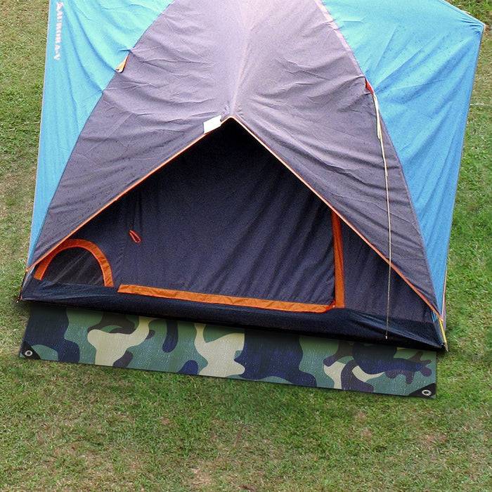 Ein blau-oranges Campingzelt auf Gras aufgebaut, teilweise offen, zeigt den Eingang. Eine Tarnung-Matte liegt vor dem Zelt.