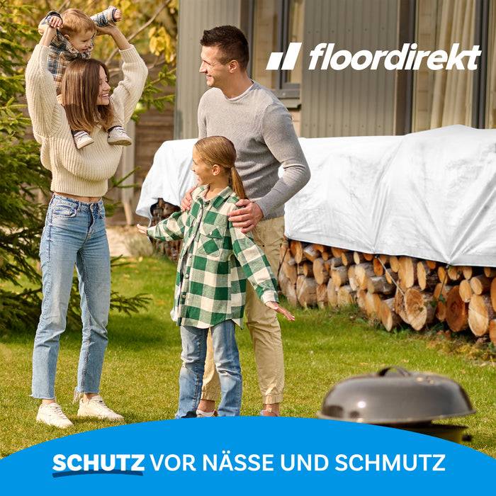 Eine vierköpfige Familie lächelt in einem Garten. Zwei Kinder umarmen ihre Eltern. Der Text „floordirekt