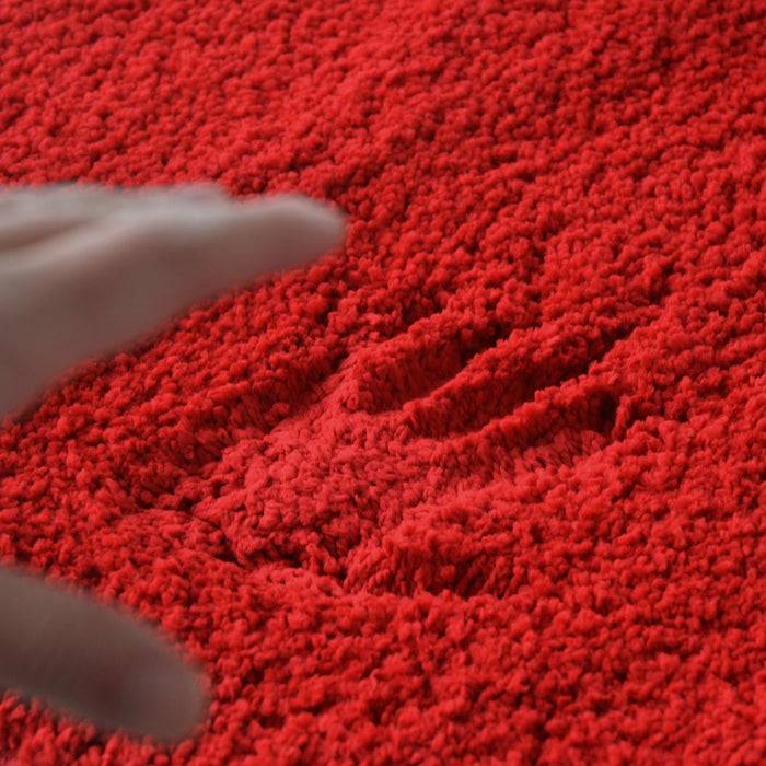 Eine Hand, die einen Abdruck auf einer plüschigen roten Oberfläche hinterlässt und dabei die Textur und Weichheit des Materials zeigt.