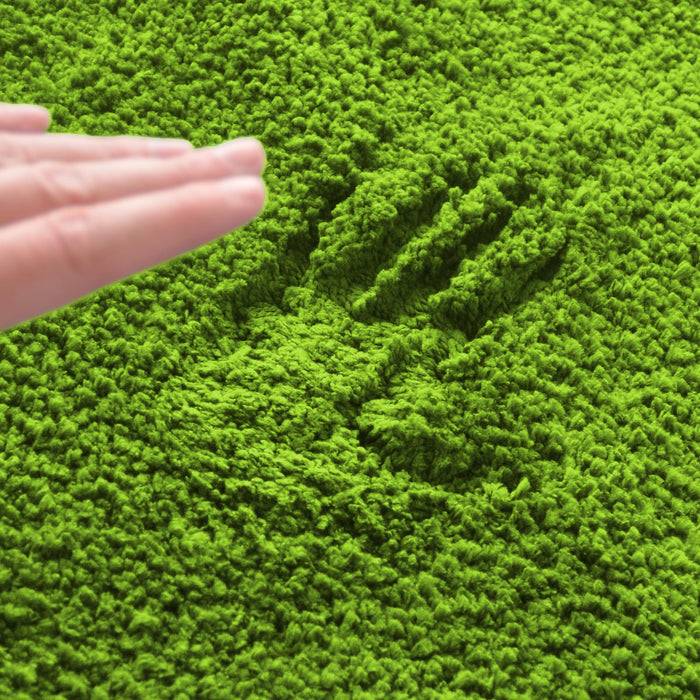 Eine grüne, strukturierte Oberfläche mit dem Abdruck einer Hand. Eine Hand streckt sich nach unten in Richtung des Abdrucks und deutet eine Interaktion mit dem Material an.